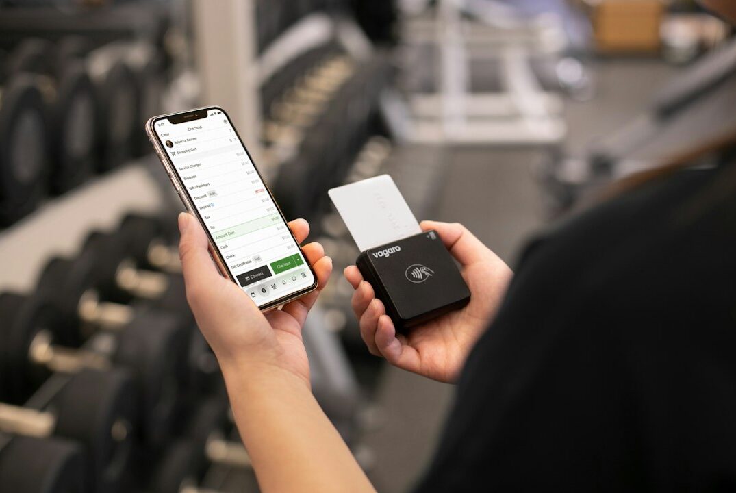 Persona usando el teléfono para gestionar un pago en un gimnasio