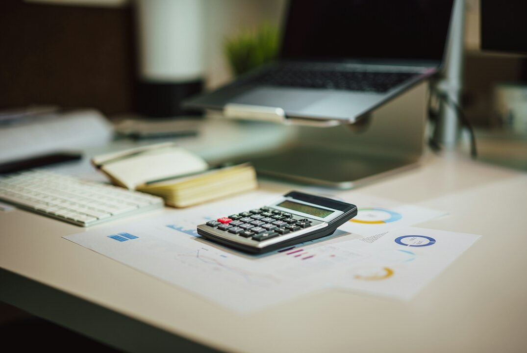 Calculadora y laptop sobre un escritorio, representando la automatización de procesos contables y de facturación