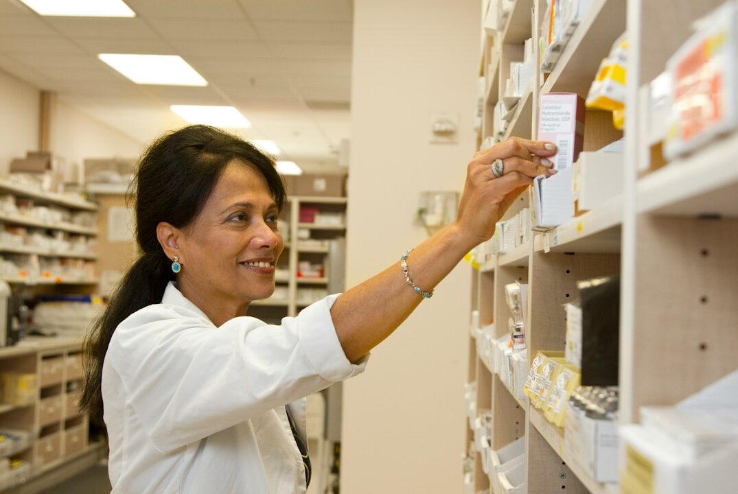 Farmaceuta revisando medicamentos en un estante de farmacia